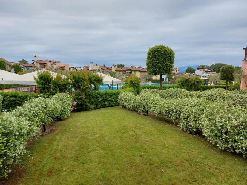 rząd krzaków z polem trawy w obiekcie Garda Resort Village I Borghi w mieście Peschiera del Garda