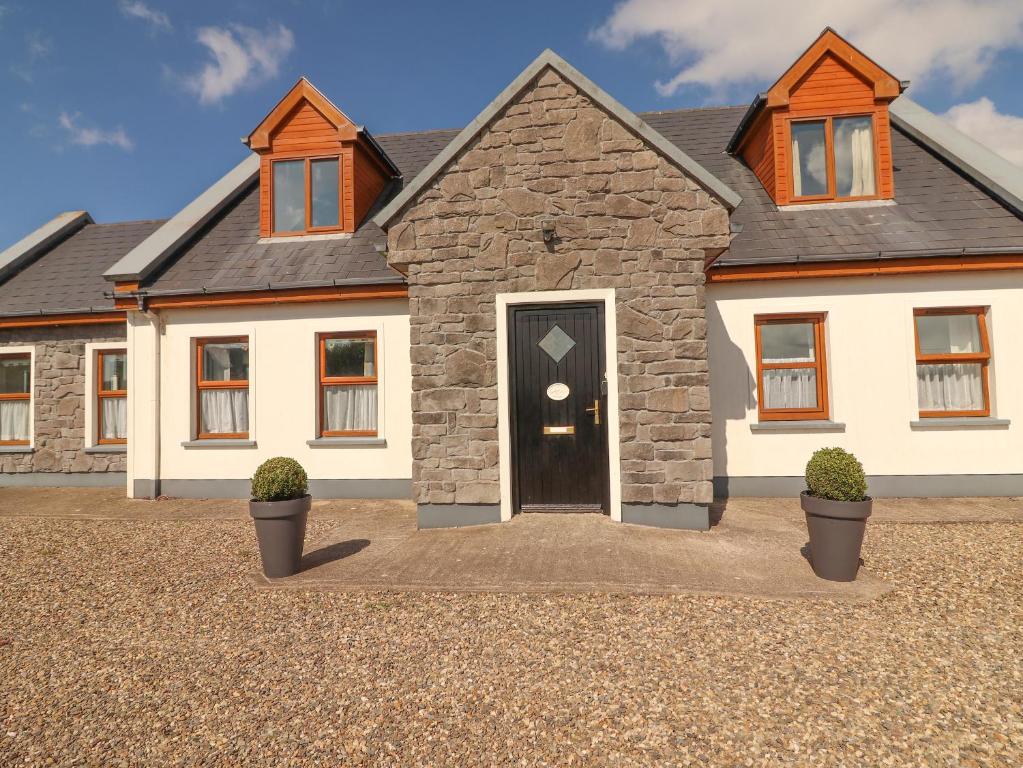 una grande casa bianca con una porta nera di Cherry Blossom Cottage a Ennis