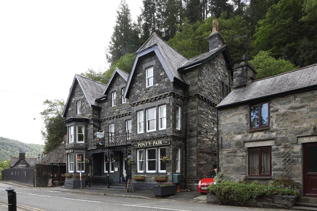 un antiguo edificio de piedra al lado de una calle en Pont y Pair Inn, en Betws-y-coed