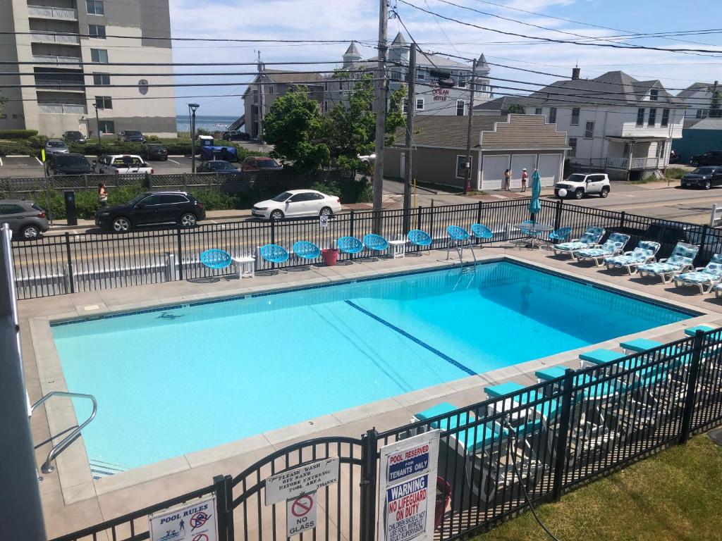 a large blue swimming pool with chairs and a parking lot at Executive Motel in Old Orchard Beach