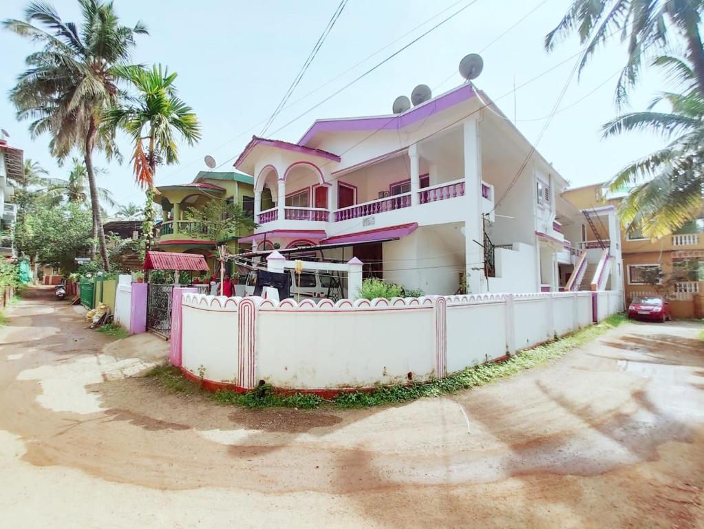 una casa con una cerca blanca delante de ella en Goa tour advisor & hospitality, en Candolim