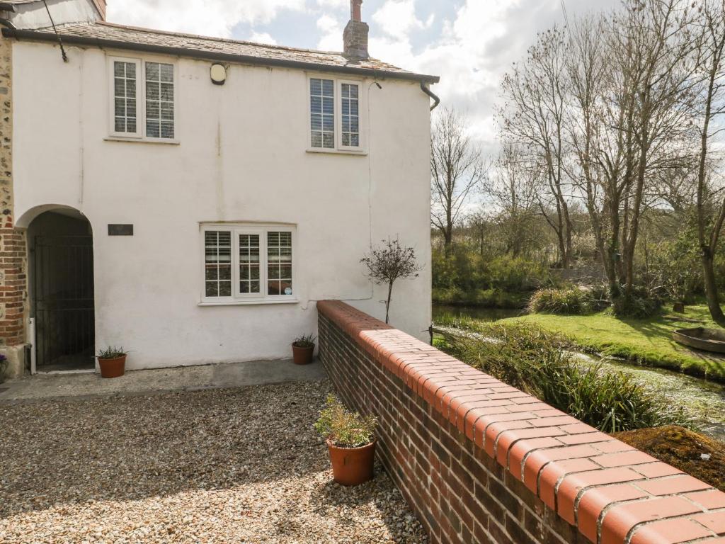 ein weißes Haus mit einem Steinzaun davor in der Unterkunft Riverside 67 Dorchester Road in Dorchester