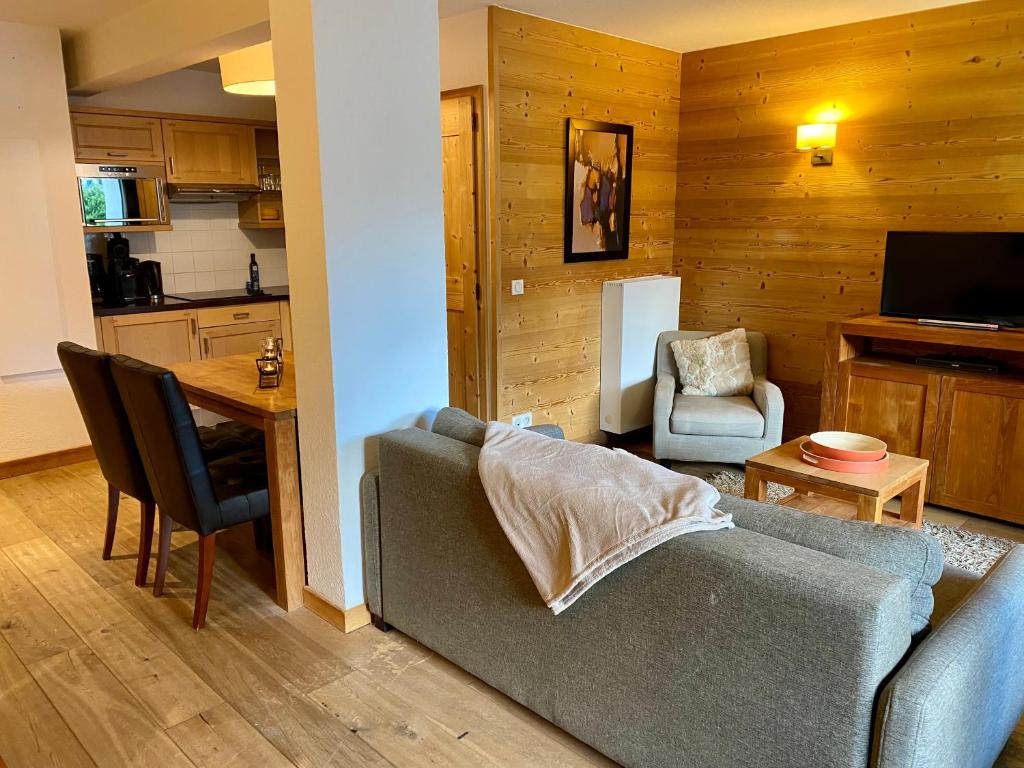 a living room with a couch and a table and a kitchen at Le REFUGE DES PORTES DU MONT BLANC in Vallorcine