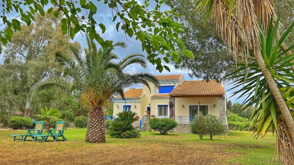 a house with two chairs and a palm tree at Villa Lefka in Melíkia