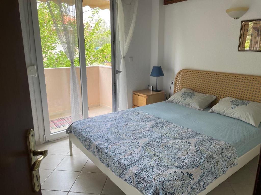 a bedroom with a bed and a door to a balcony at Pamys House in Kalamitsi