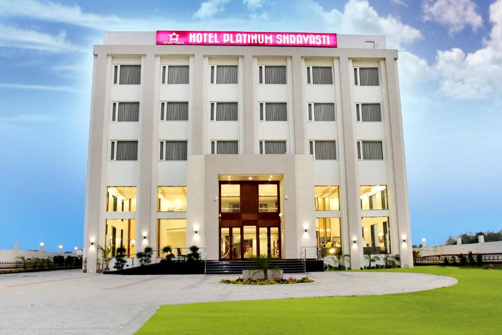 a white building with a pink sign on it at Hotel Platinum Shravasti in Katra