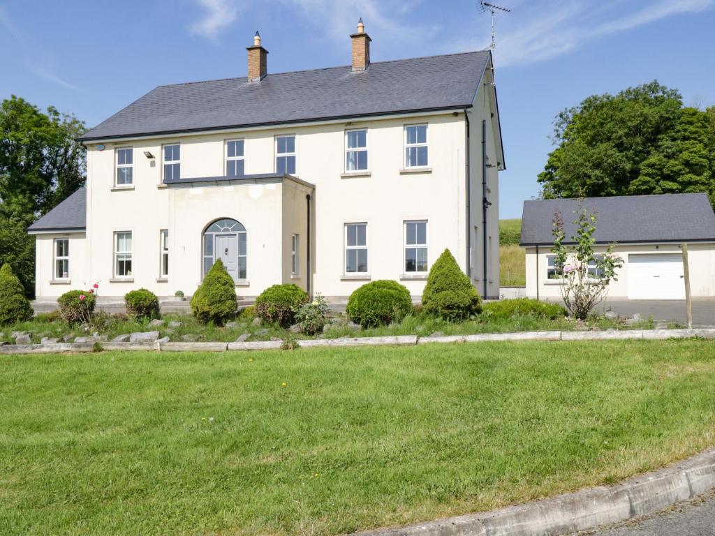 uma grande casa branca com um relvado verde em Drumlaney em Belturbet