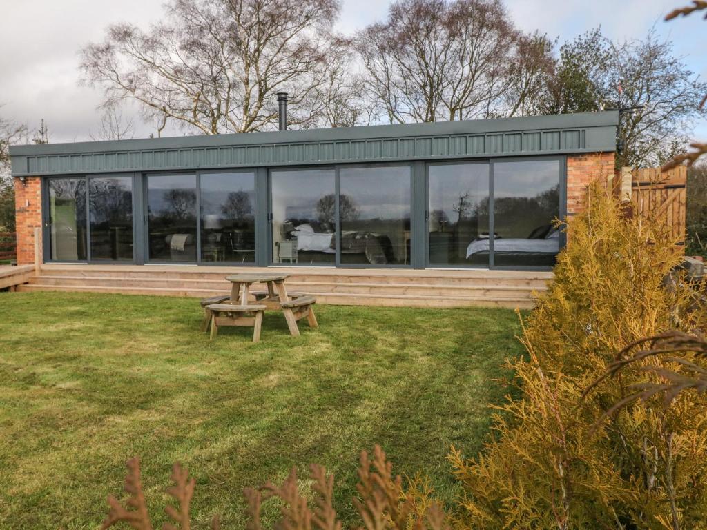 ein Haus mit einem Picknicktisch im Gras in der Unterkunft Saddlers in Stone