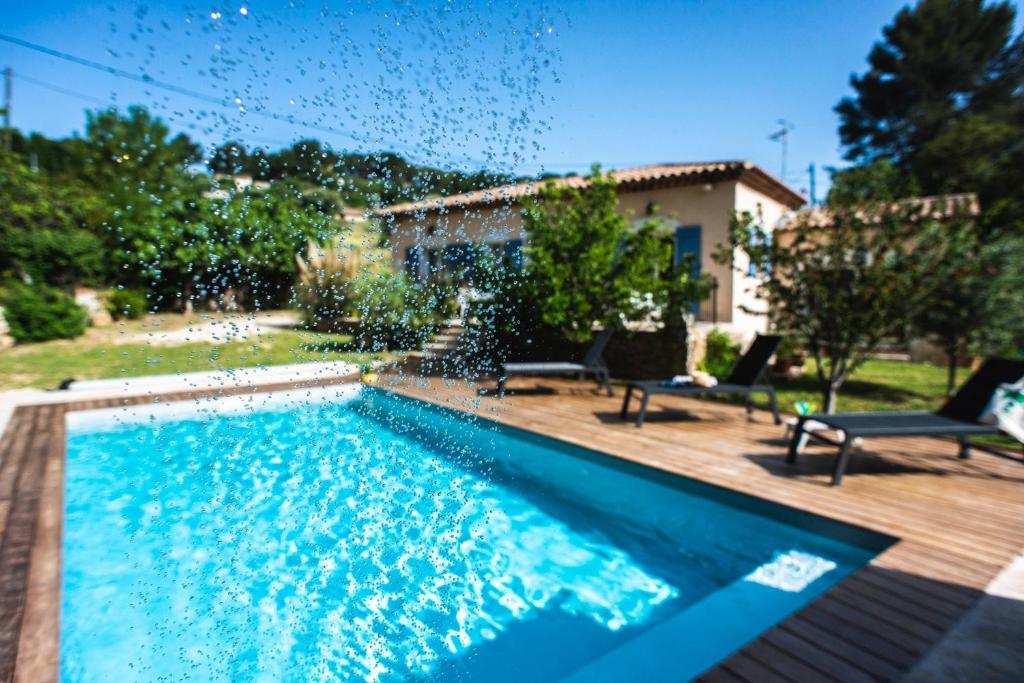 a swimming pool with two chairs and a house at Les Manaux en Provence in Roquevaire