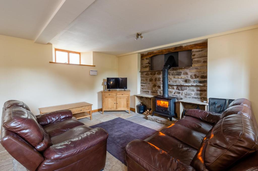 a living room with a leather couch and a fireplace at Chapel Beck, Millthrop in Sedbergh