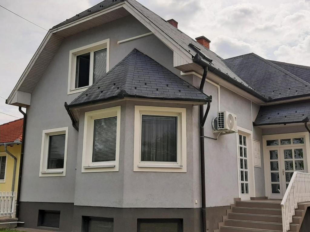 a gray house with a gray roof and windows at Blue House in Győrzámoly