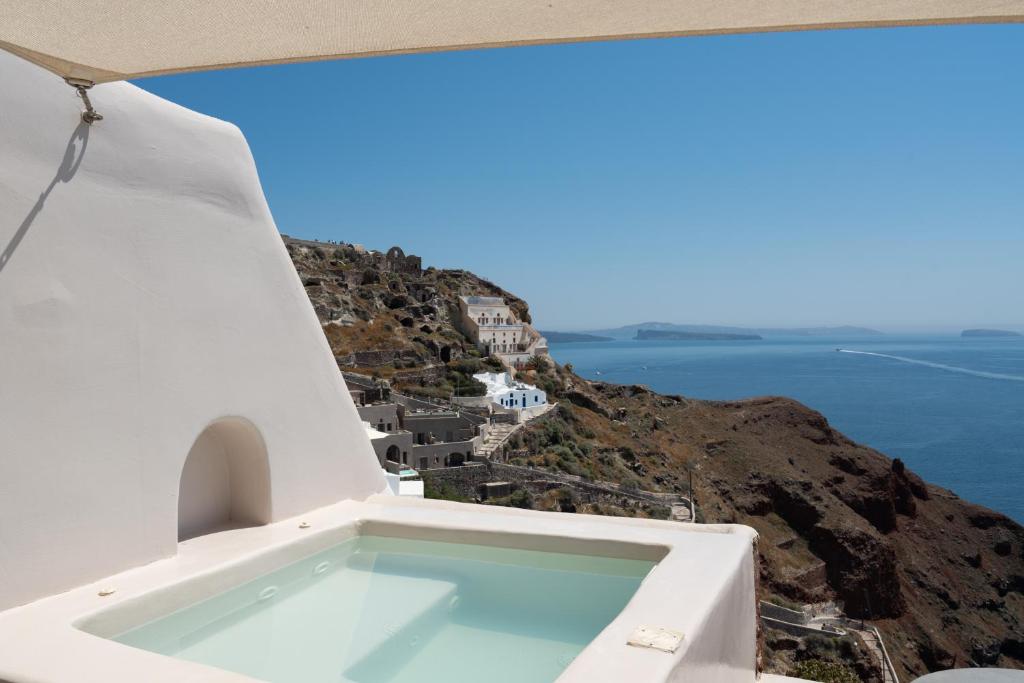 a swimming pool on the side of a cliff with the ocean at The Architect's Cave House in Oia