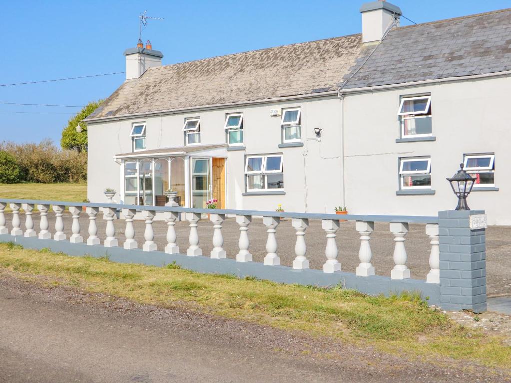 una casa blanca con una valla blanca en Gleann Griannmhar, en Rosscarbery
