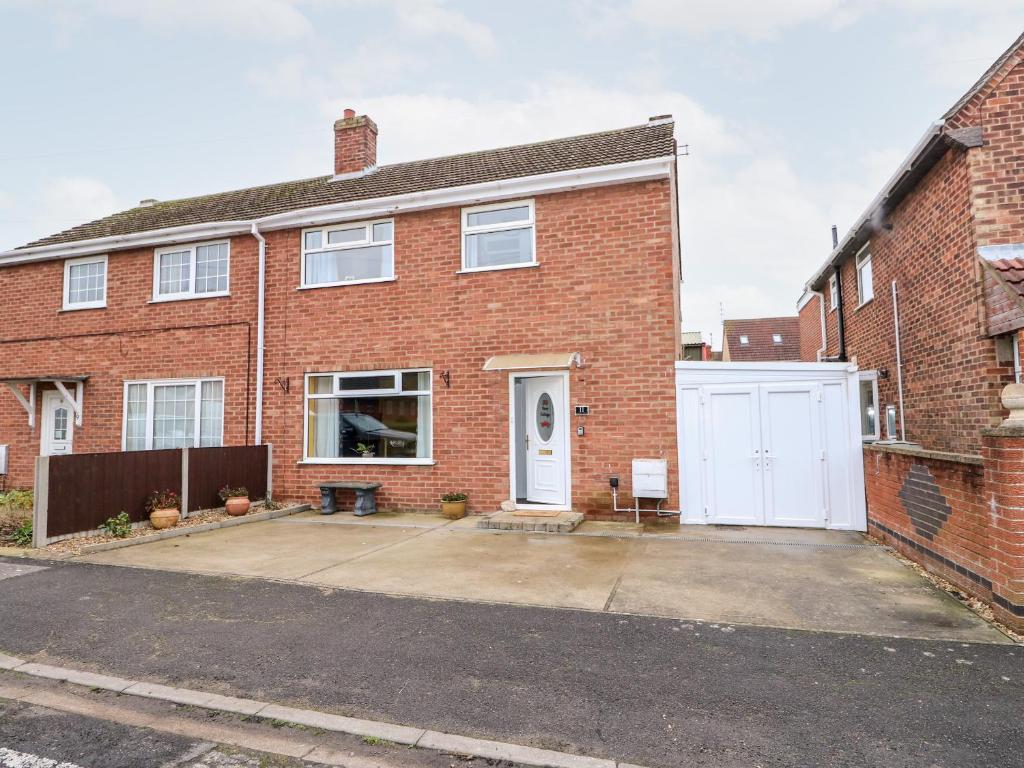 a red brick house with a white garage at Rose Cottage in Skegness