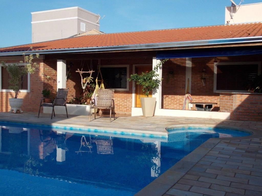 a swimming pool in front of a house at Cantinho rústico simples & aconchegante in Brotas