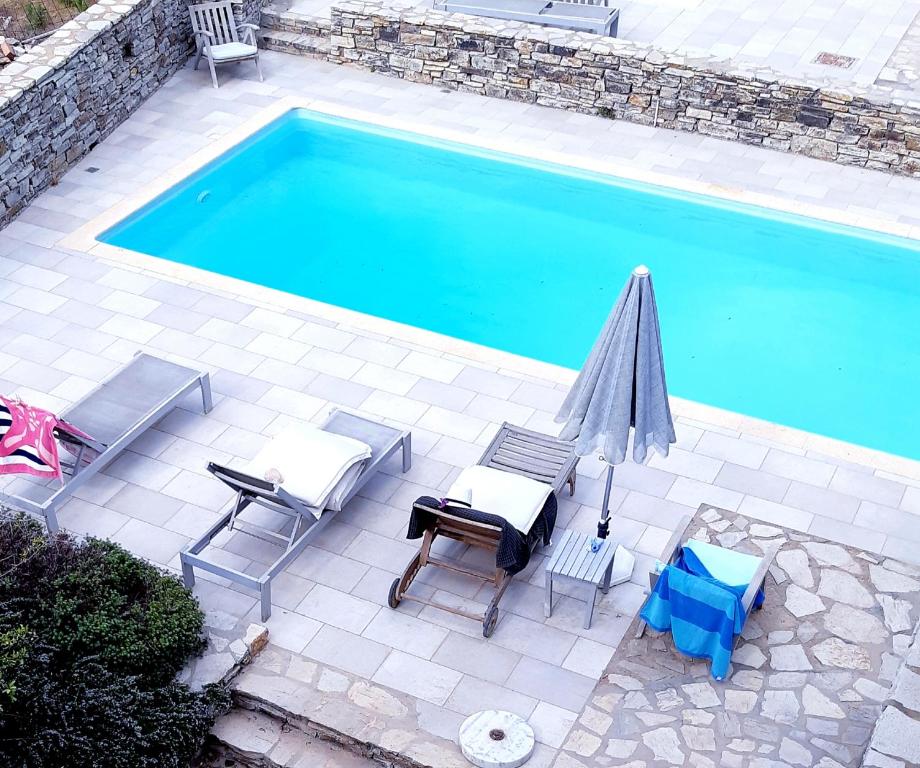 Villa Sofi in Saint George Antiparos (pool&sea) في أنديباروس: اطلالة علوية على مسبح مع كراسي ومظلة