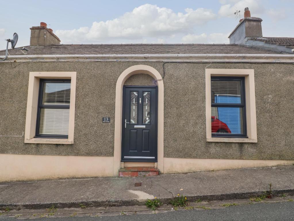 a house with a blue door and two windows at Holly Cottage in Pembroke
