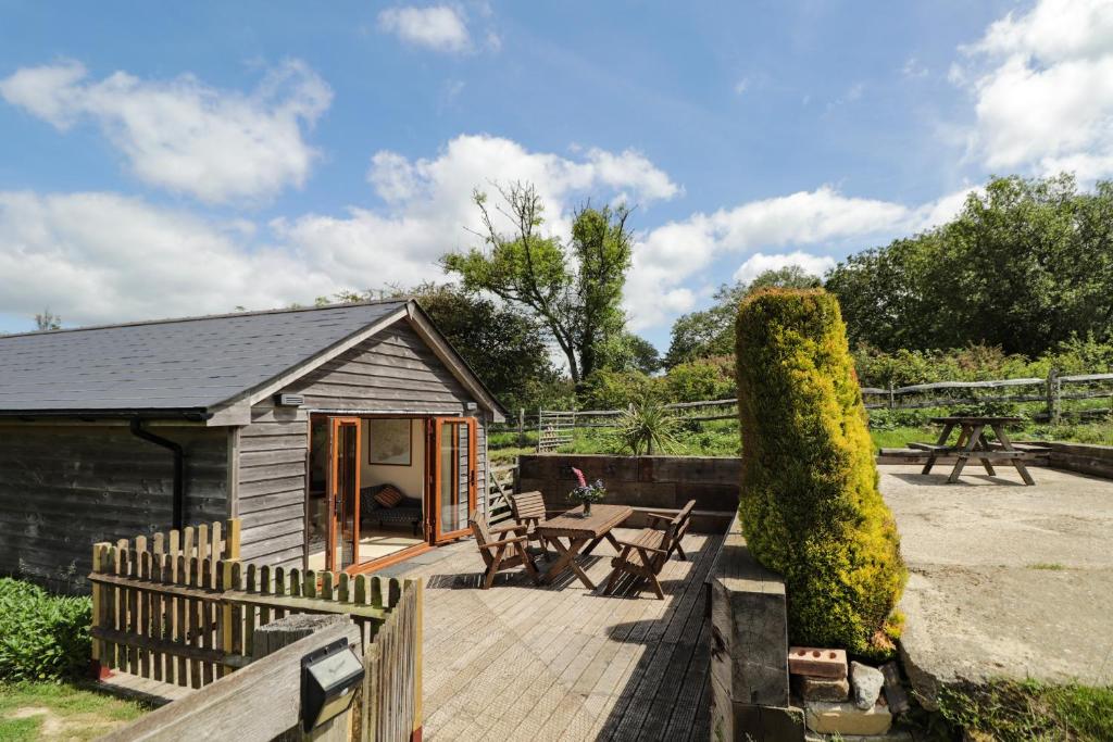 a cabin with a wooden deck with a table and chairs at Loose Farm Lodge in Battle