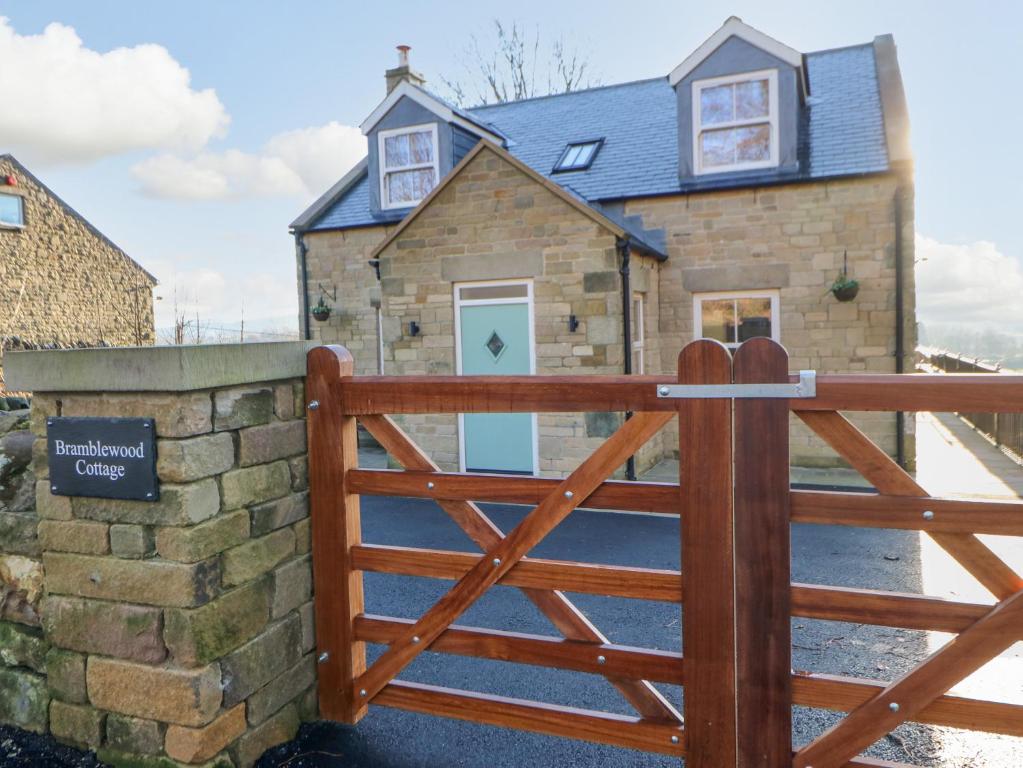 a gate to a stone house with a wooden fence at Bramblewood Cottage in Middleton in Teesdale