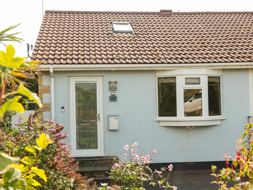 a blue house with a window and a roof at Tillys Cottage in Weston-super-Mare