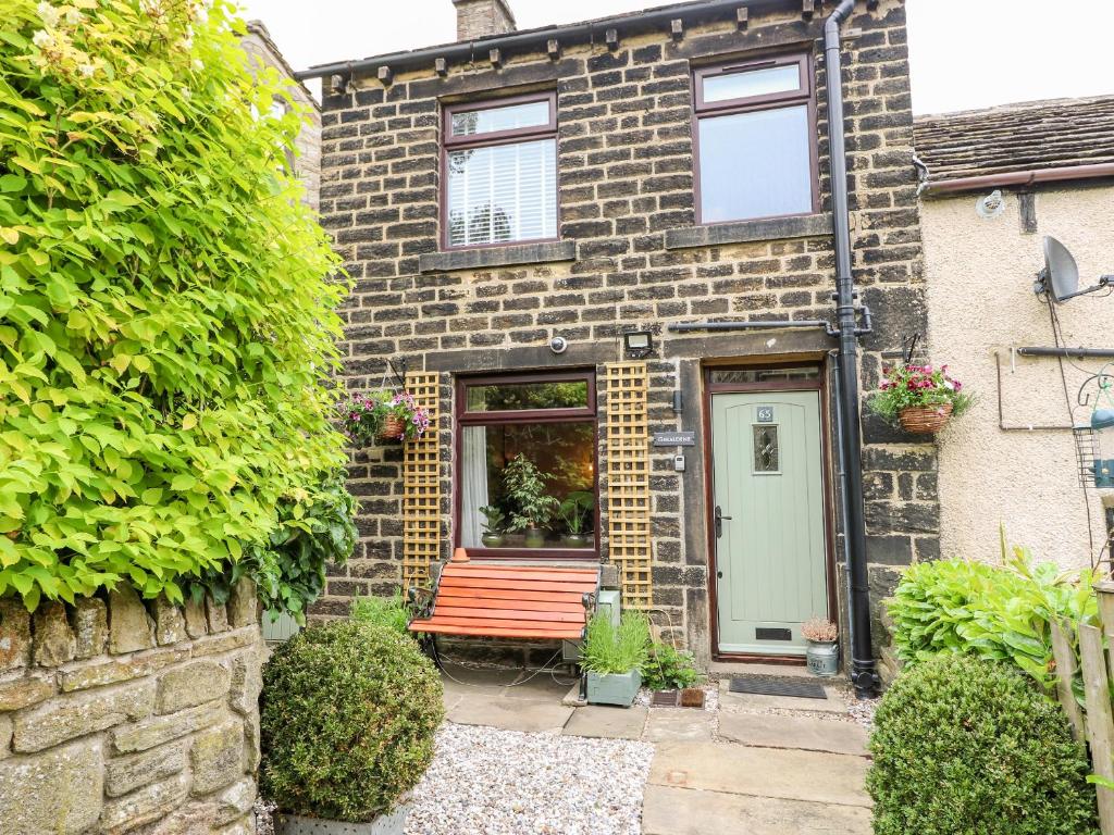 a brick house with a red bench in front of it at Geraldene in Holmfirth