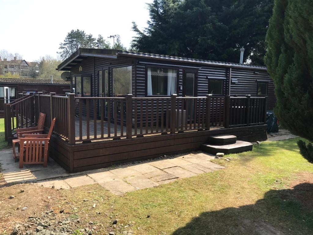 a wooden cabin with a deck and a chair at Pheasant Lodge in Builth Wells