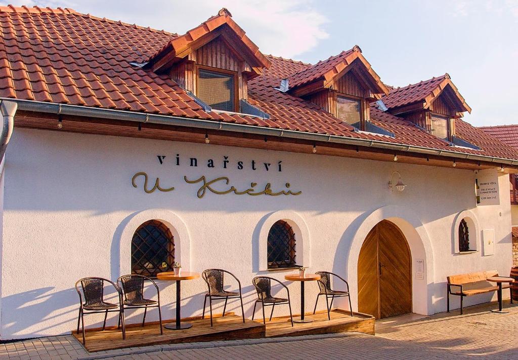 un bâtiment blanc avec des chaises et des tables. dans l'établissement Apartmán vinařství U Krčků, à Zaječí