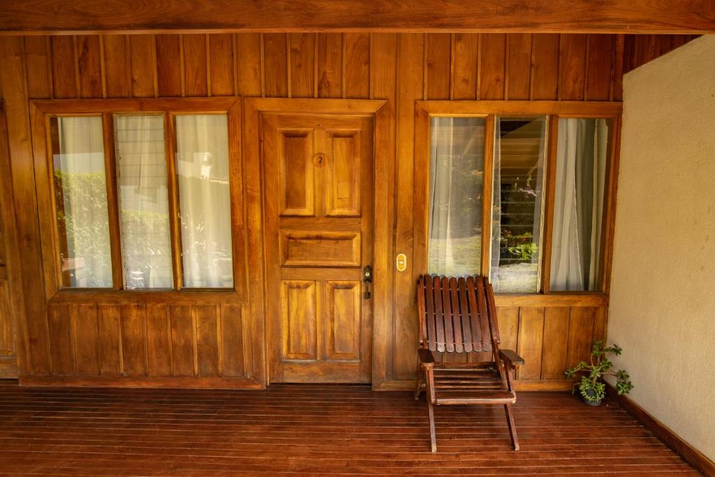 una silla sentada frente a una puerta de madera en Cowboy Hostel - Habitaciones con Baño Privado, en Monteverde
