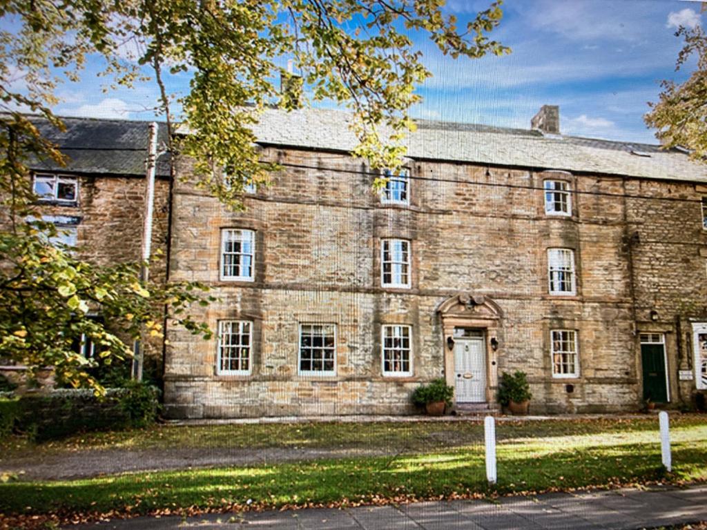 a large brick building with a white door at Hotspur House in Allendale Town