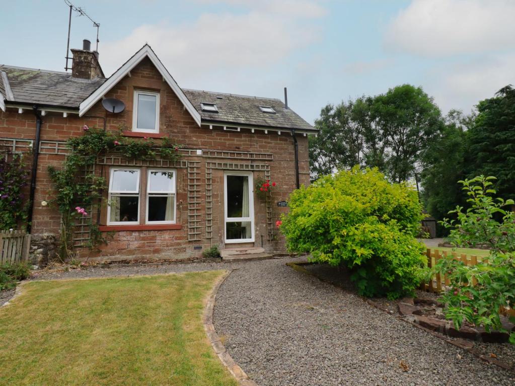 a brick house with a garden in front of it at Lucys cottage in Canonbie