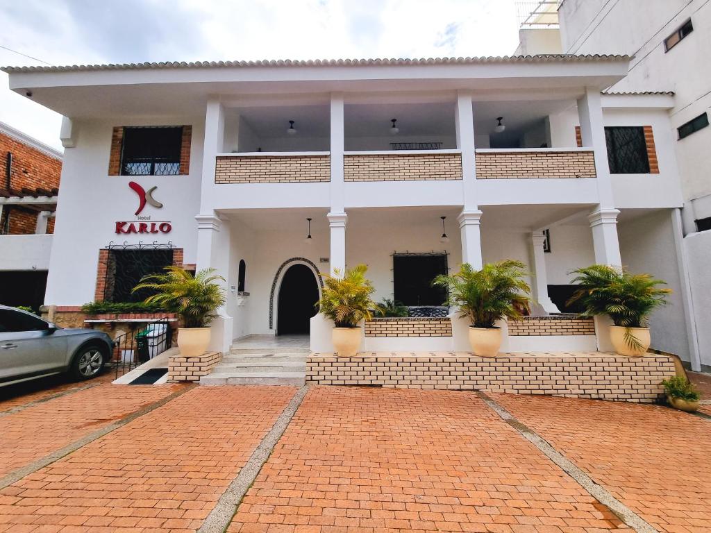 a white building with potted plants in front of it at Hotel Karlo in Cali