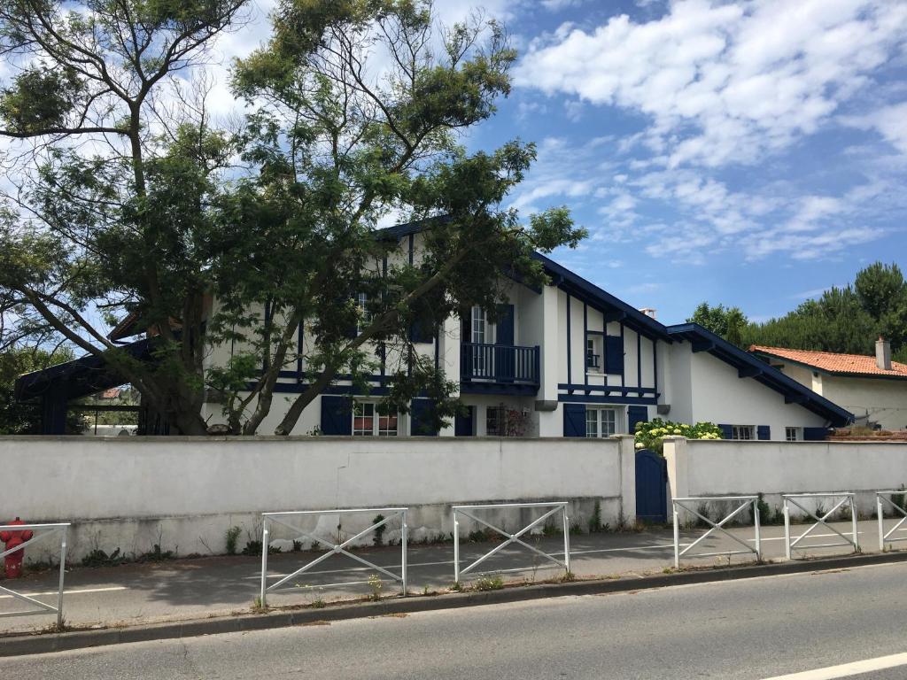 a white house with a tree behind a fence at Haritza in Anglet