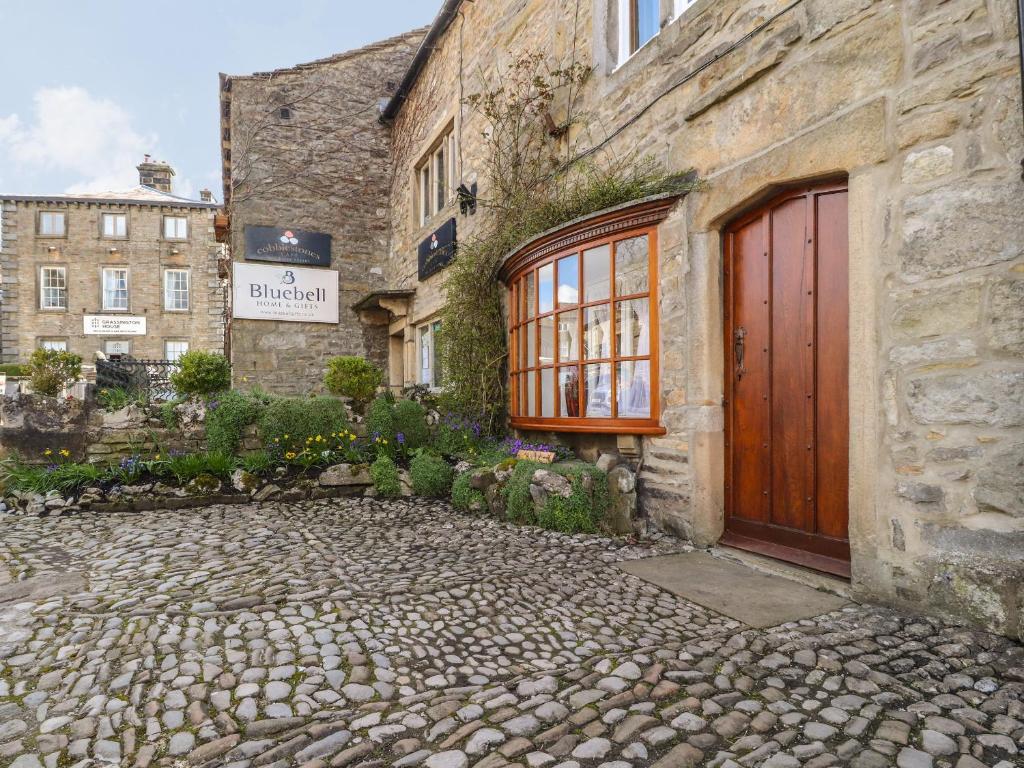 a stone building with a red door on a street at 2 The Square in Skipton