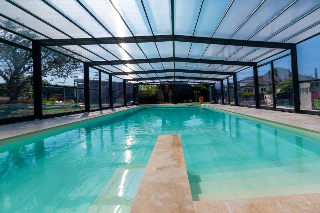 une piscine intérieure avec un toit en verre dans l'établissement Les Pilotis Du Cognac, à Bourg-Charente