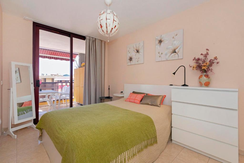 een slaapkamer met een groot bed en een groene deken bij Centrico, primera línea del mar in Puerto de Santiago