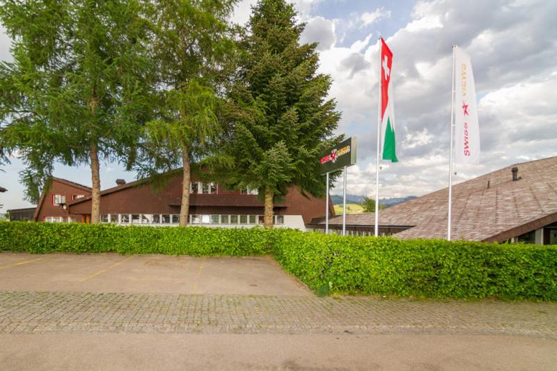 duas bandeiras estão a voar em frente a um edifício em Hotel Swiss Views em Hemberg