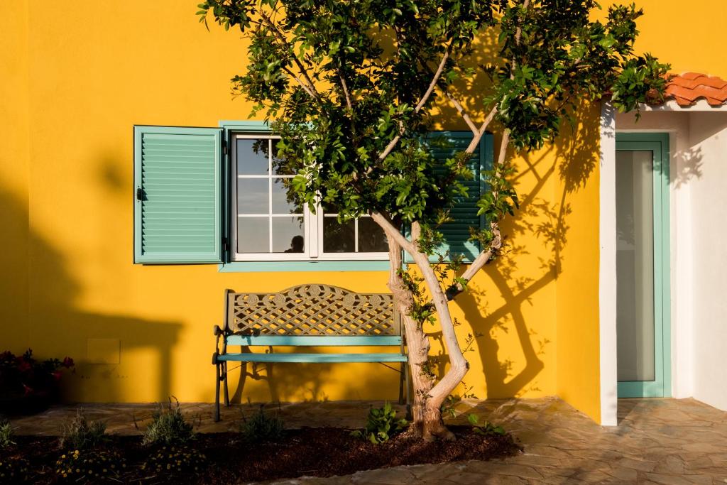 una panchina di fronte a un edificio giallo con un albero di La Finquita - Adeje ad Adeje