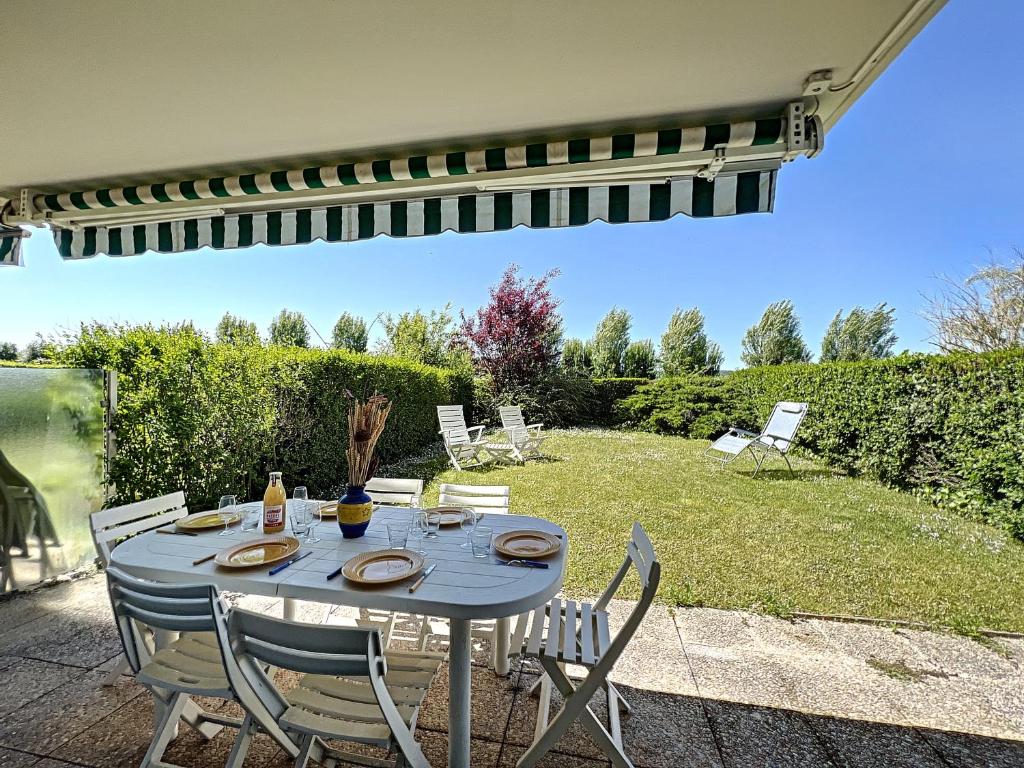 een tafel en stoelen op een patio bij Zéllie - YourHostHelper in Deauville