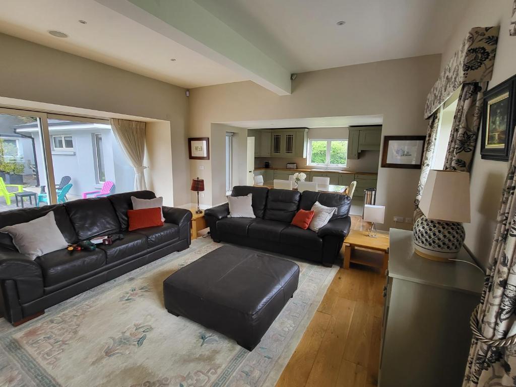 a living room with a black leather couch and a table at The Coach House in Dublin