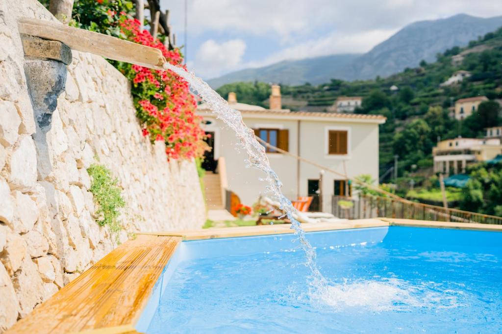 a pool with a water fountain in front of a house at Villa Le Murelle in Tramonti