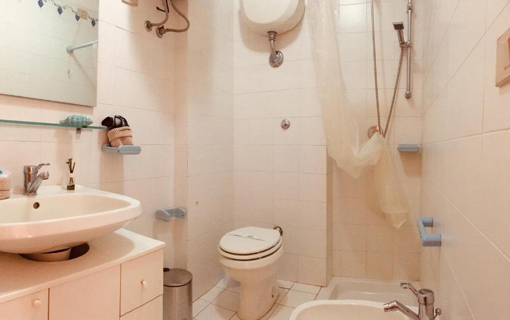 a white bathroom with a toilet and a sink at Holiday House in Alghero