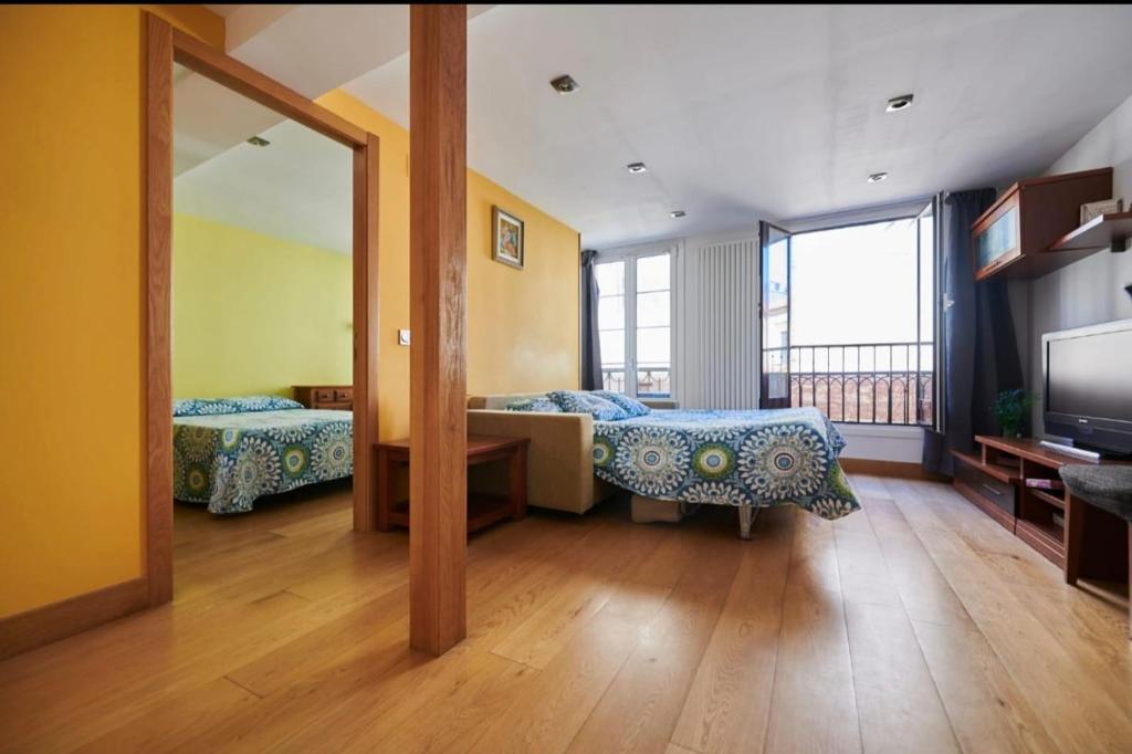 a large room with two beds and a mirror at Pensión San Vicente in San Sebastián