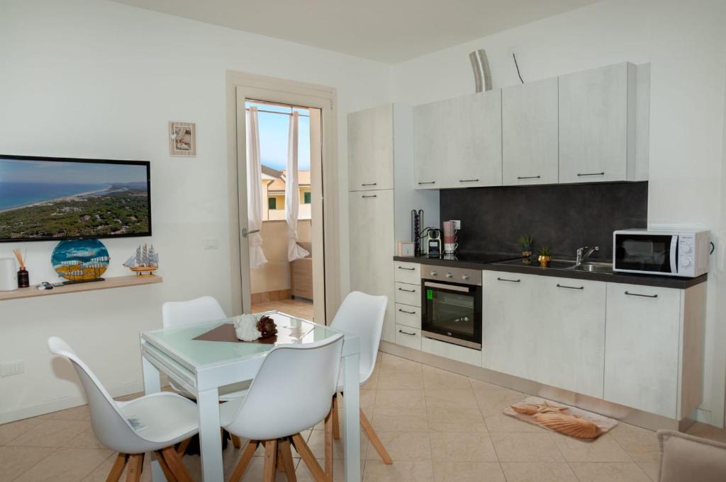 kuchnia z białymi szafkami, stołem i krzesłami w obiekcie Appartement Baia delle mimose H9 w mieście Sassari