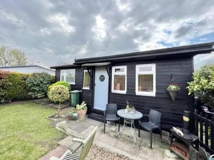 a black tiny house with a table and chairs at 2 bedroom chalet bungalow on Humberston Fitties. in Humberston
