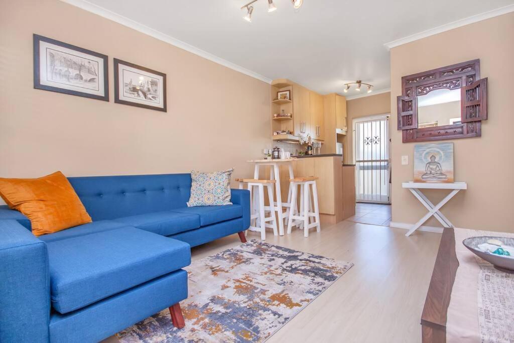 sala de estar con sofá azul y cocina en Working Professionals, Modern, Cozy, WiFi, en Ciudad del Cabo