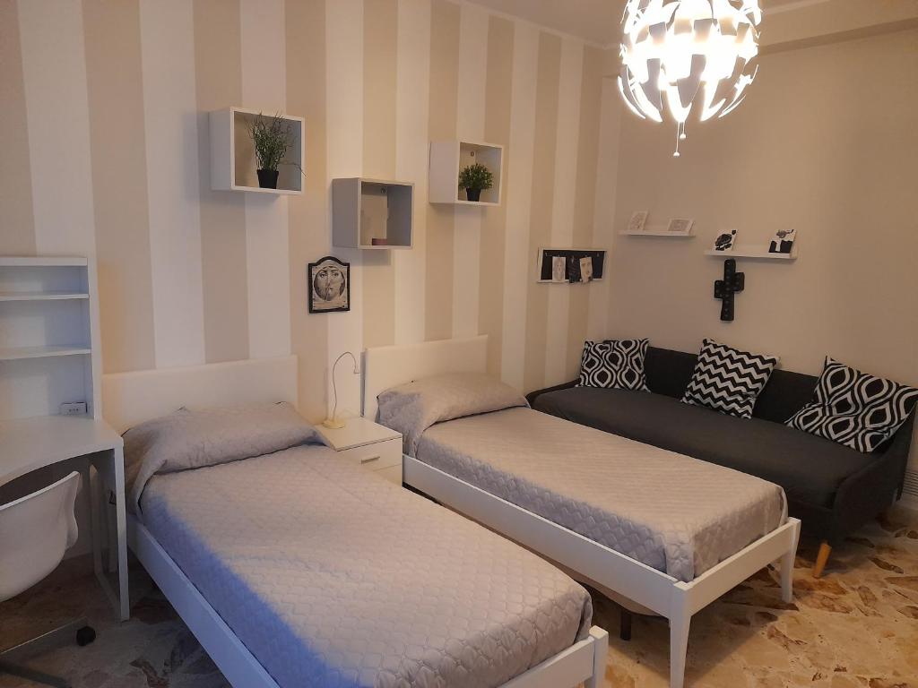 Pokój z 2 łóżkami, kanapą i żyrandolem w obiekcie La Casa di Luzzo w mieście Agrigento