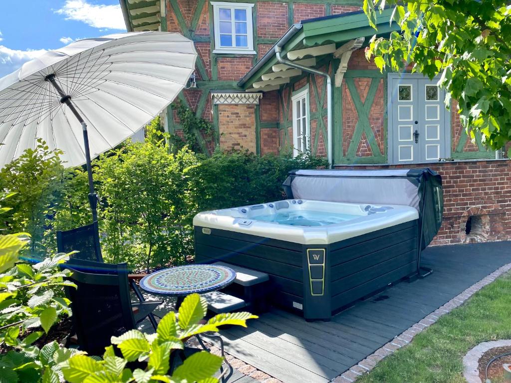 a hot tub in the backyard of a house with an umbrella at Villa B das zauberhafte Chalet in Vetschau