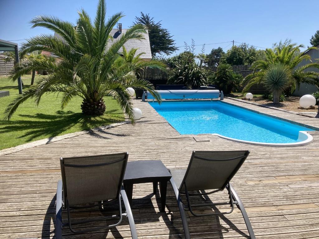 2 sillas y una mesa junto a la piscina en Villa de 5 chambres a Bretteville sur Ay a 400 m de la plage avec piscine privee jardin clos et wifi, en Bretteville-sur-Ay