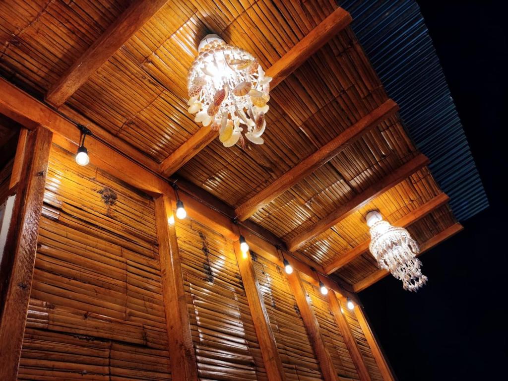 a chandelier hanging from a wooden ceiling with lights at ALOJATE BEACH in Zorritos