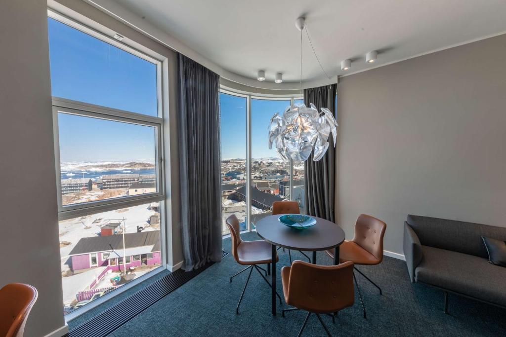 a dining room with a table and chairs and a large window at Best Western Plus Hotel Ilulissat in Ilulissat